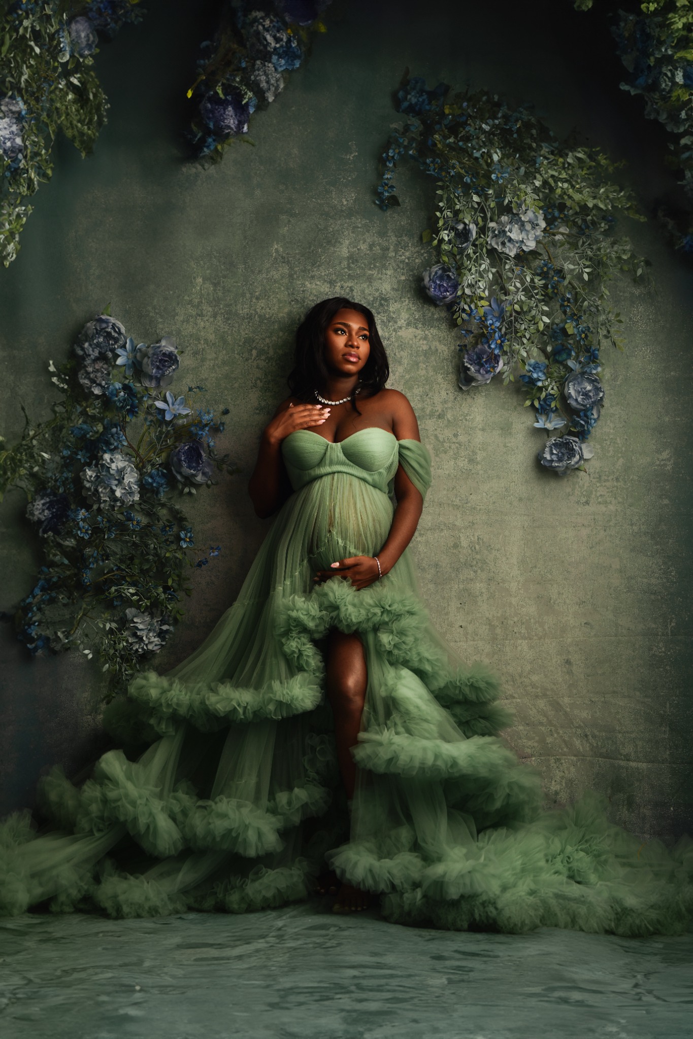 Pregnant woman surrounded by rich green floral styling