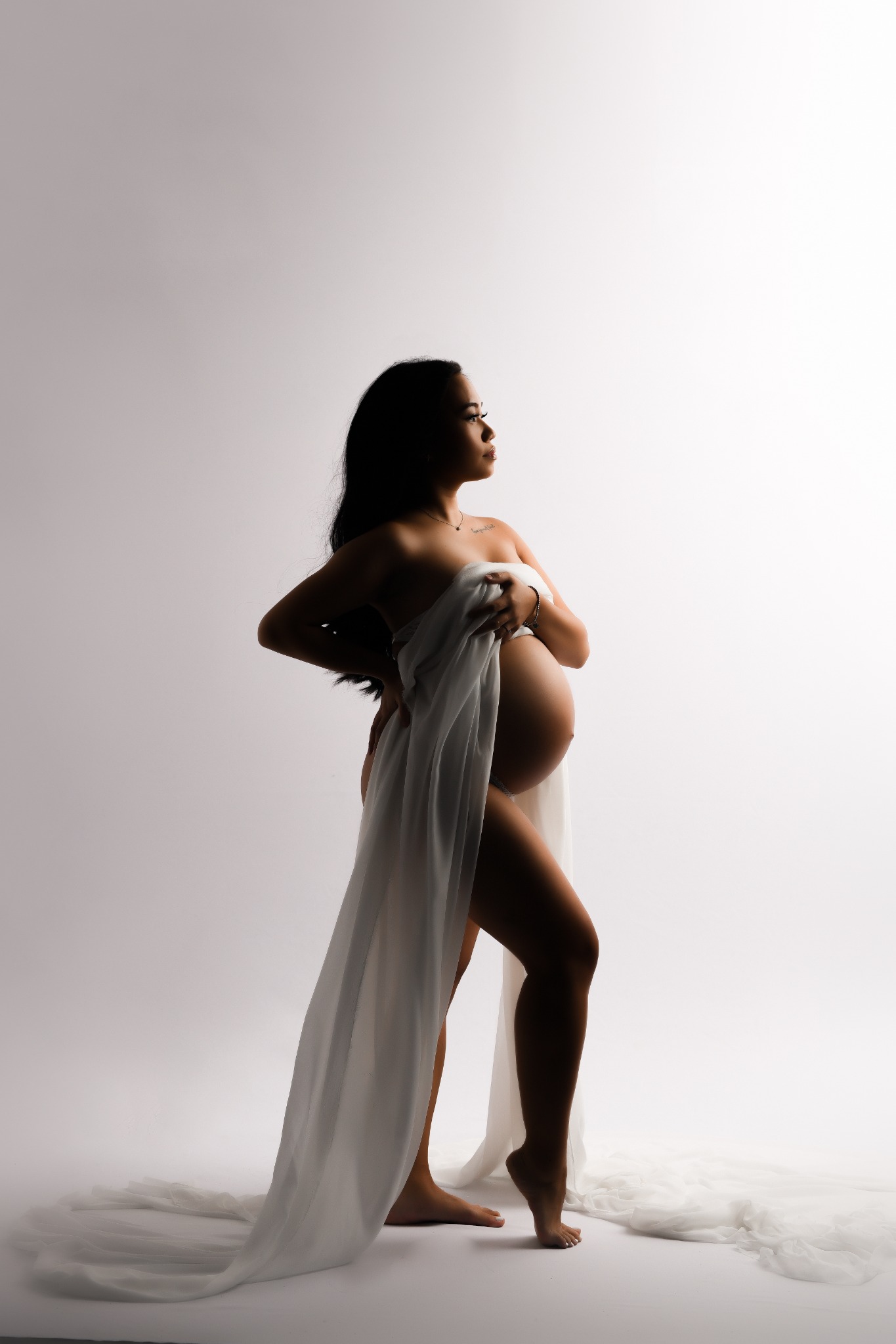 Artistic maternity silhouette in flowing white fabric