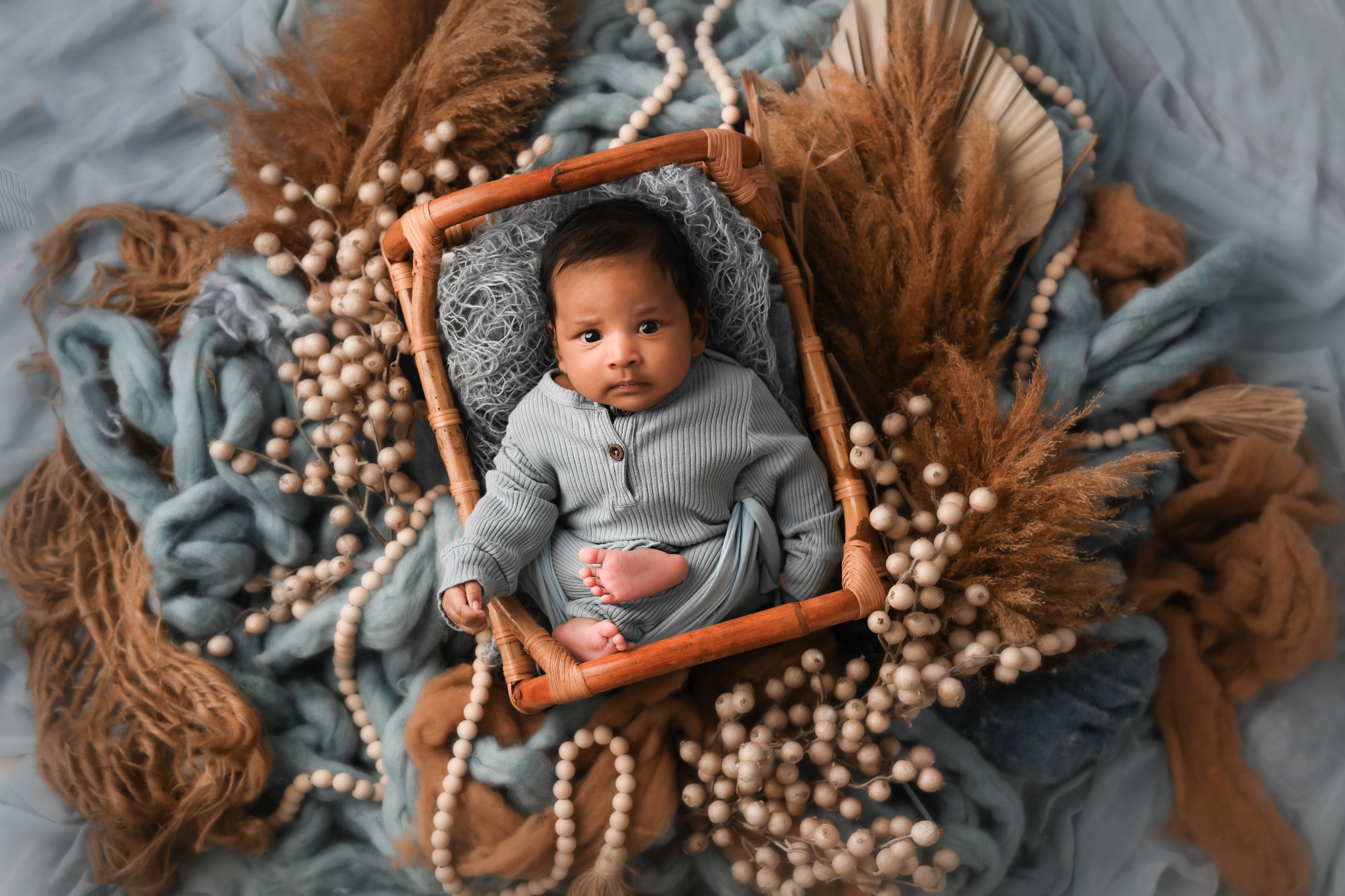 Newborn baby posed in a blue and earth-toned studio set