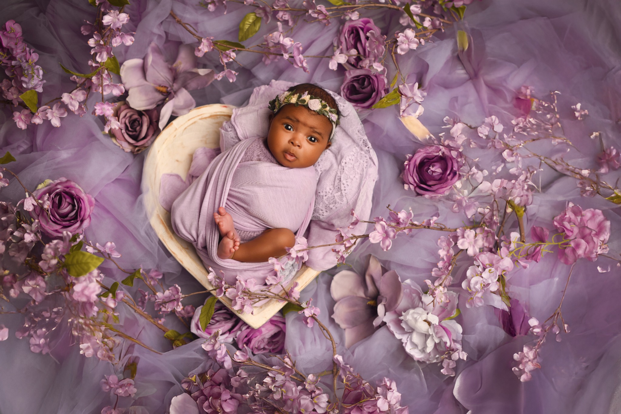 Newborn baby wrapped in lavender floral swaddle in a Laval studio