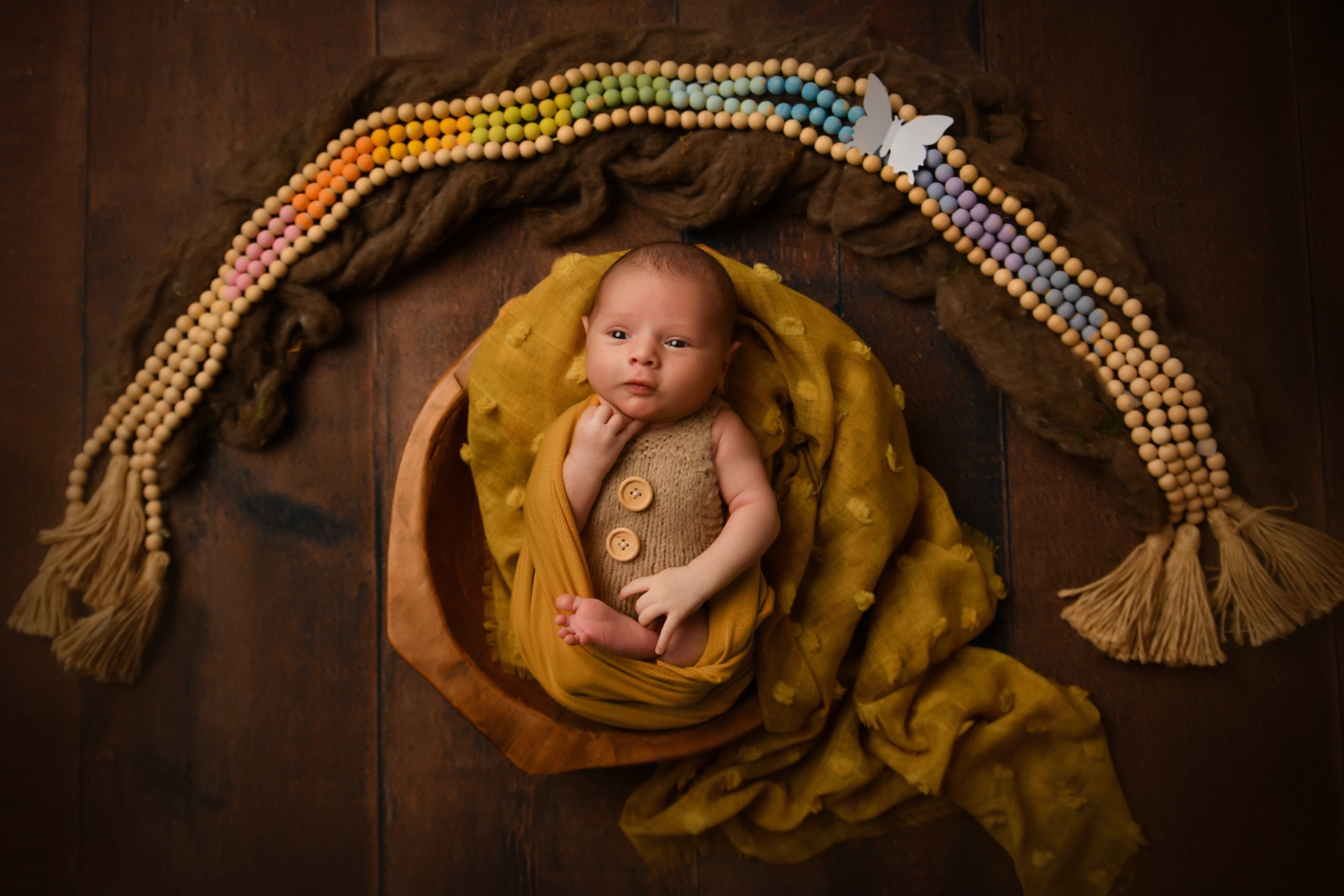 Newborn baby posed in a mustard rainbow studio décor